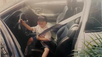 Lucas sits in a car.