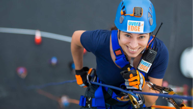 smiling woman rappeling down a tall building