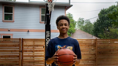 Wish Kid Solomon holding a basketball on his new basketball court