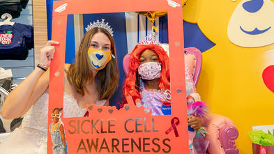 Amina with princess and sickle cell awareness poster