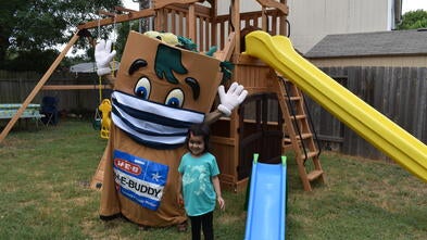 Wish Kid Sophia and HEBuddy standing in front of Sophia's new playset