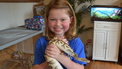 wish kid Mazie smiling and holding a snake