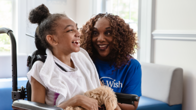 smiling child in a wheelchair with happy volunteer