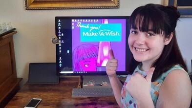 Kera, sitting in front of gaming computer, with thumbs up
