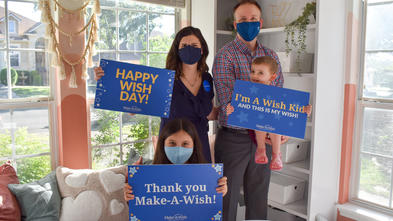 Elise and her family standing with "Thank You Make-A-Wish" signs.