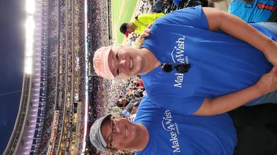 Jon and Vicki at a Twins baseball game wearing their Make-A-Wish shirts and smiling.