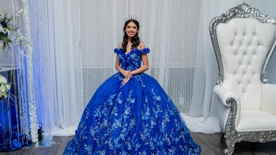 Wish kid Alexis standing in her blue quinceañera dress smiling