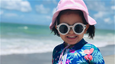 Jocelyn in swim gear smiles on a Hawaii beach