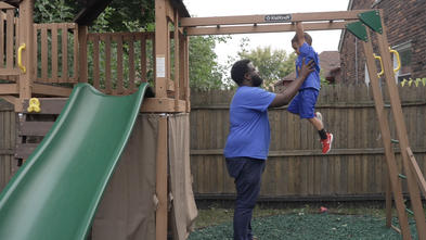 Father and son wearing Make-A-Wish blue t-shirts on a play set