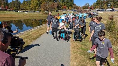 Wish kid Marcy pictured front center walking in her pink Trexo with a large group following behind her