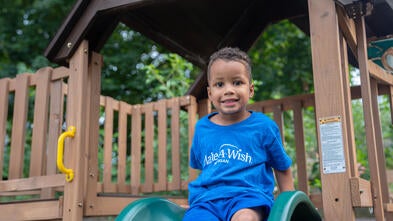 A young boy sitting on his slide about the slide down