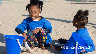 Wish kid Cherish on the beach playing with a toy shovel and bucket.