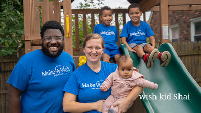 wish kid Shai on his new playset smiling with his family.