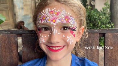 wish kid Zoe has on face paint and a Make-A-Wish shirt. She is smiling and very happy.