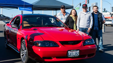 Ignacio with his family during his wish reveal standing next to his restore Mustang