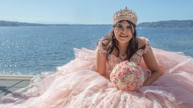 Jacqueline in a pink dress sitting at the waterfront.