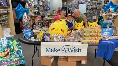 Arthur posing behind a table full of Pokemon cards with his mom and stepdad
