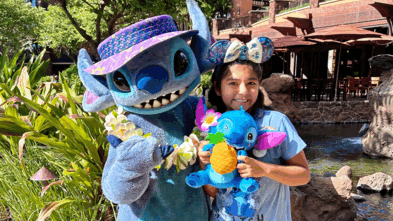 Sophia standing next to Stitch holding her Stitch stuffed animal