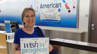 Janet DeYoung standing in front of the Wish Wall with trophy