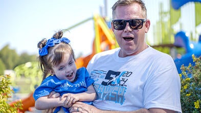 A wish dad sits smiling with his daughter.