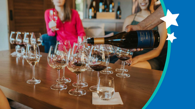 Person pouring a bottle of wine into glasses on a table. 