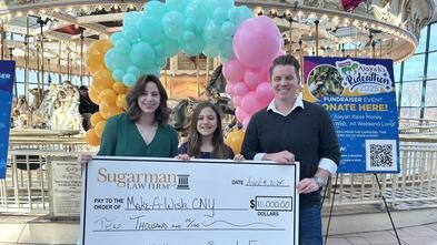 Three people standing with Check in front of balloons and carousel