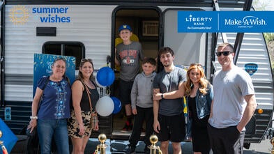 Chayse standing in the doorway of a camper with his family standing in front