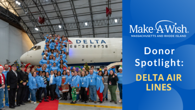 A photo of some of the Delta Air Lines employees at Logan Airport,posing in front of a plane in the Delta hangar