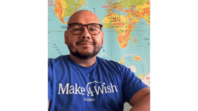 Juan smiling in front of a world map