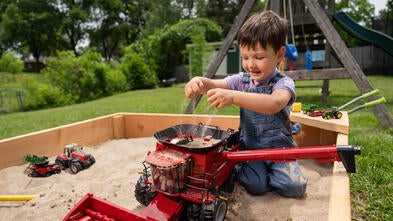 Wish kid Henry playing with a combine toy in the sandbox