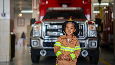 A young boy smiling in front of a fire truck 