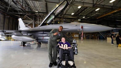 Nash smiling with Justin Jefferson at an airplane hangar in front of a fighter jet