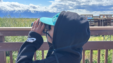 Aanya looks through binoculars on her wish trip to Alaska