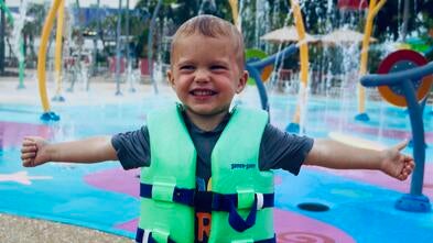 Knox at a waterpark in his life jacket with his arms stretched out