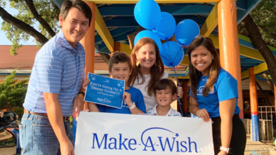 Wish Kid Avery and family with wish manager Nikki at Chuy's holding a Make-A-Wish sign.