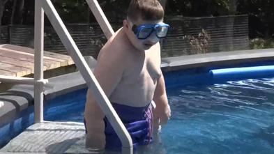 Anthony climbs down the steps into his new pool 