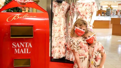 Elizabeth and sister Claire standing next to the Macy's Believe letter box in front of Elizabeth's dress display.