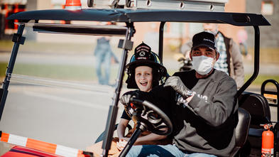 Brayson gets a ride in his firefighter-themed golf cart. 