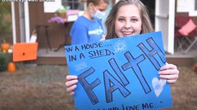 Faith holds a poster in front of her she shed on her wish day