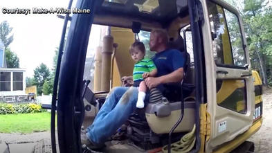 Kellen sits on the lap of the driver of a construction vehicle