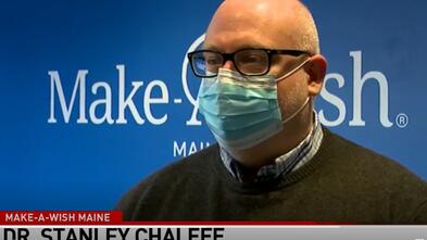 Dr. Stanley Challeff speaks in front of the Make-A-Wish Maine logo