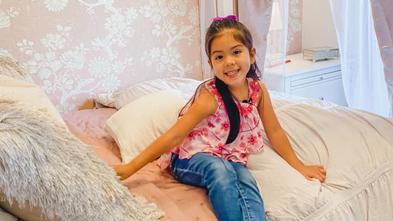 Wish kid Arianna sitting on her new pink bed.