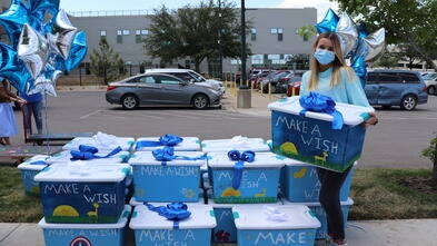 Lauren standing next to her boxes full of comfort items for the kids at Dell Children's.