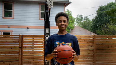 Solomon holding basketball on his brand new court.