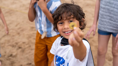 Wish Kid Nikhil holding up a gold coin he found in the sand.