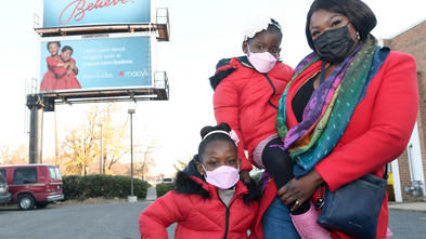 Abi, her twin, and her mother pose at Abi's billboard