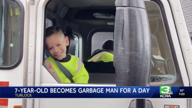 Carter waves from the window of the garbage truck on his wish day