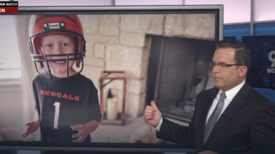 Reporter showing photo of Brixton with Bengals helmet on