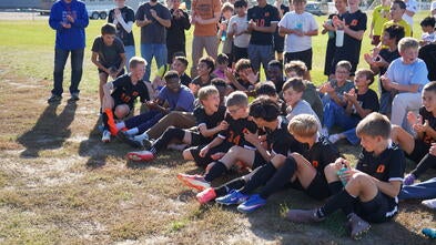 soccer players sitting on field with excited faces
