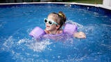 wish kid Alice swimming in above-ground pool wearing purple floaties and blue sunglasses